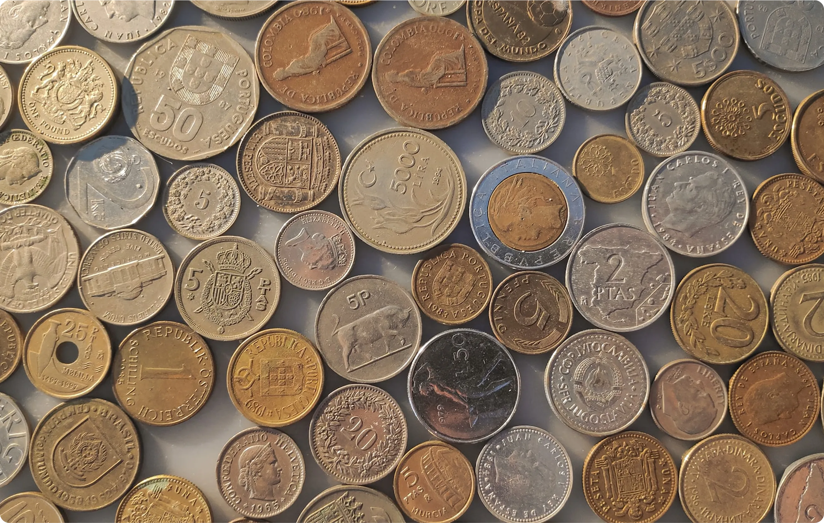 Assorted international currency coins symbolizing global trade and tariff impact – featured on Space Inventive's blog on economic policy